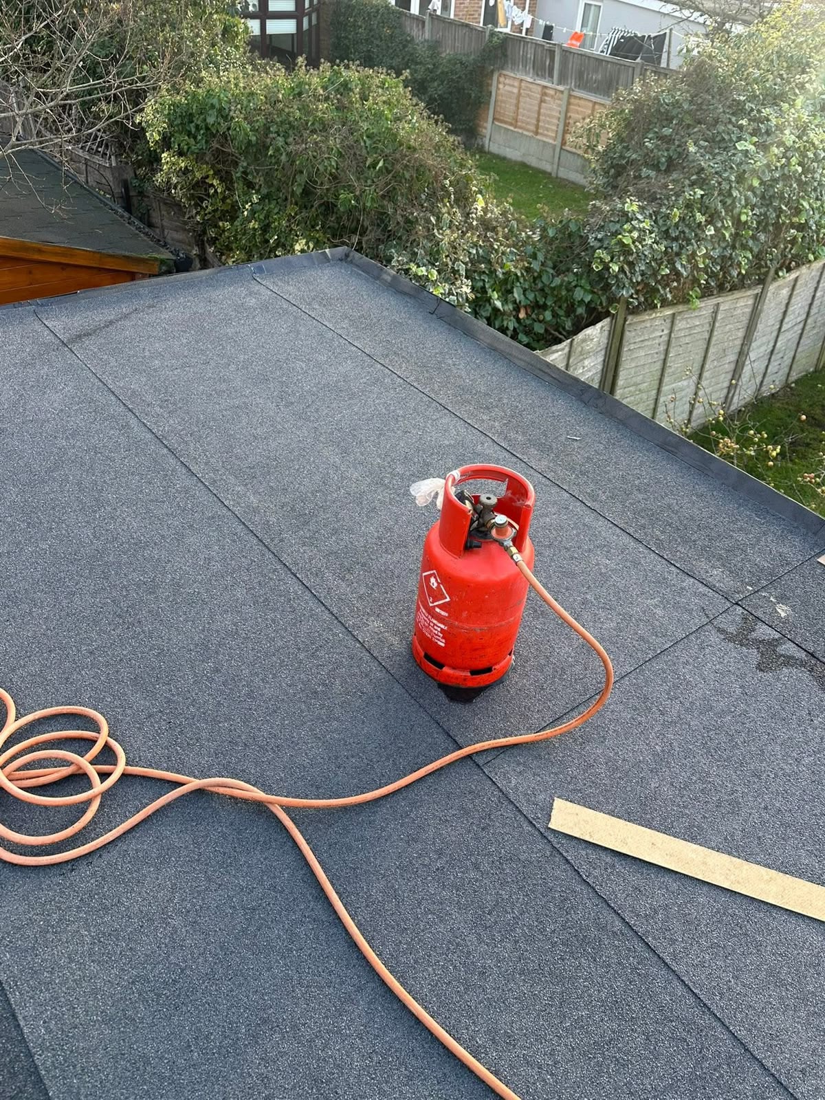 Flat roof installation in Glasgow: newly torched-on felt flat roof with gas bottle and torch on the finished deck